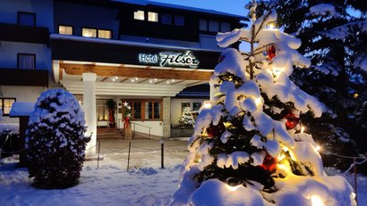 Hotel Filser im Schnee mit beleuchtetem, schneebedecktem Weihnachtsbaum