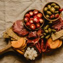 Brett mit Antipasti, Käse, Wurst, Oliven, Perlzwiebeln und Crackern